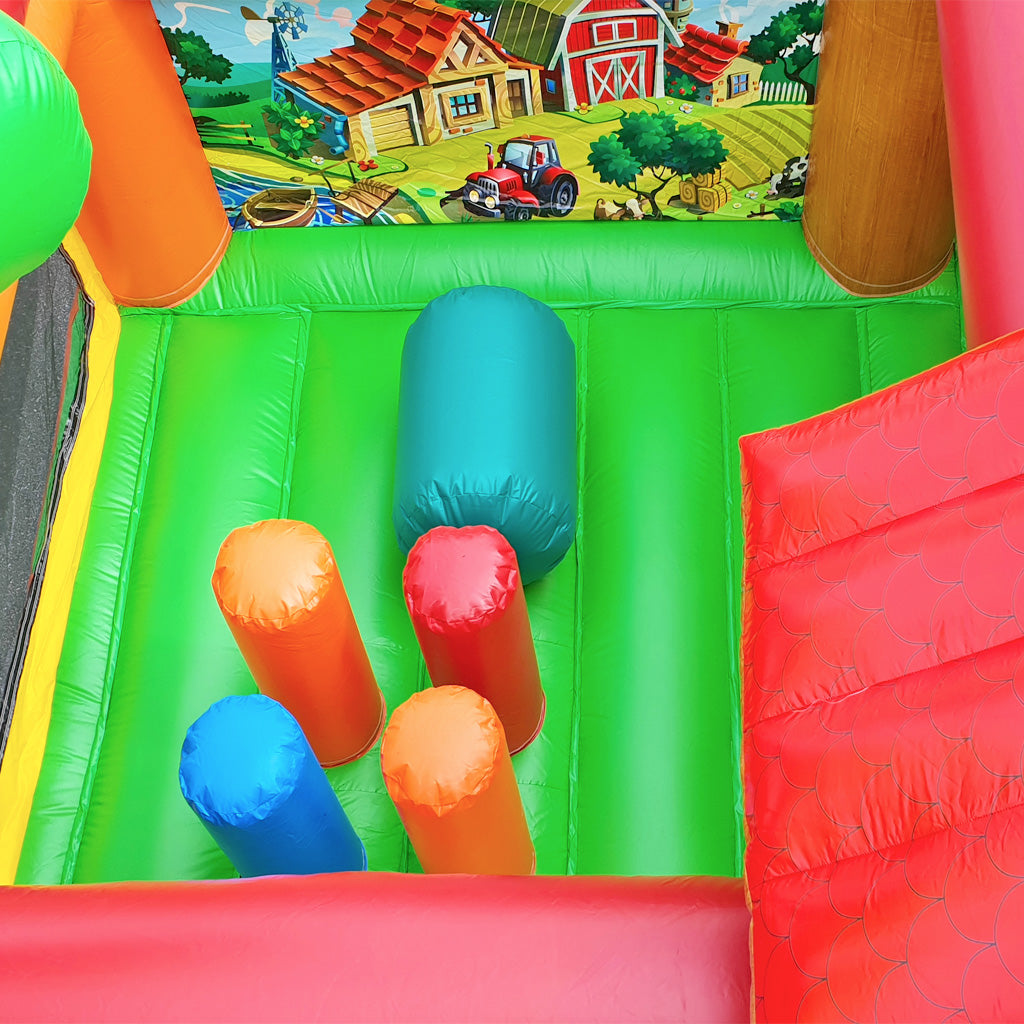 Eine grüne Hüpffläche mit Hindernissen und einem Bemalten Bauernhof auf der Rückwand.