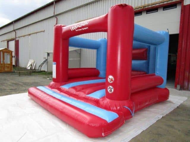 Farbenfrohe Hüpfburg vor einer Halle auf einer Plane