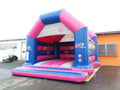 Aufblasbare Hüpfburg in Pink-Blau-Weiß vor einer Halle