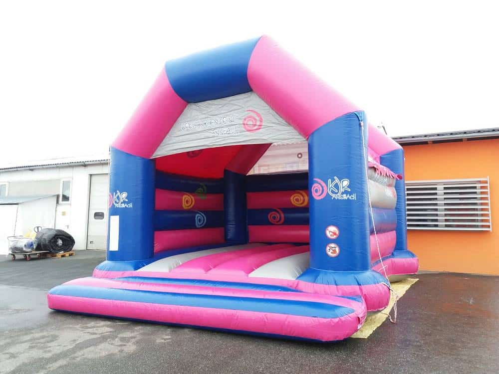 Aufblasbare Hüpfburg in Pink-Blau-Weiß vor einer Halle
