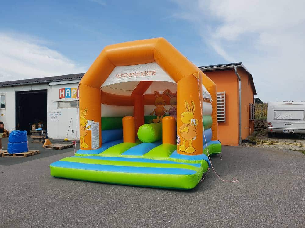 Farbenfrohe Hüpfburg auf einem Betonplatz und ein Wohnwagen