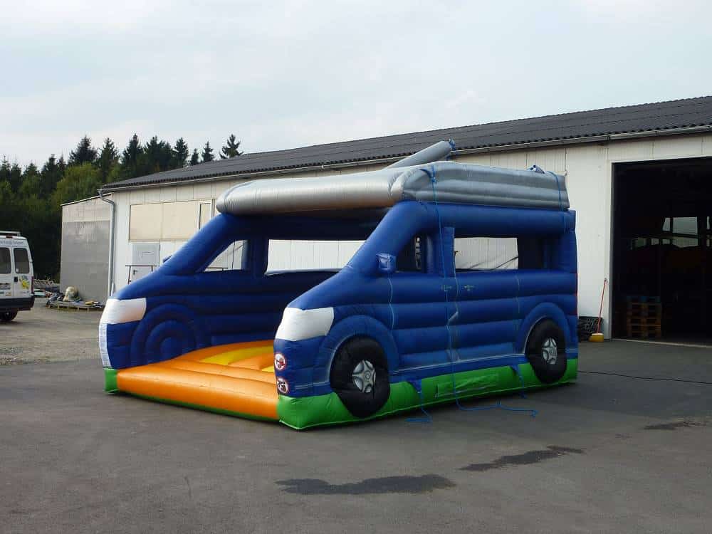 Farbenfrohe Auto Hüpfburg auf auf einem Betonplatz vor einer Halle mit großem Tor