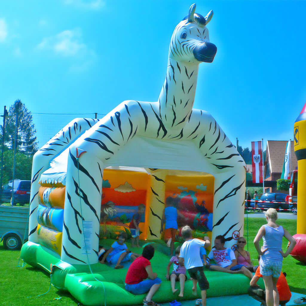 Hüpfburg mit weißen Dach, einem aufblasbaren großen Zebrakopf.