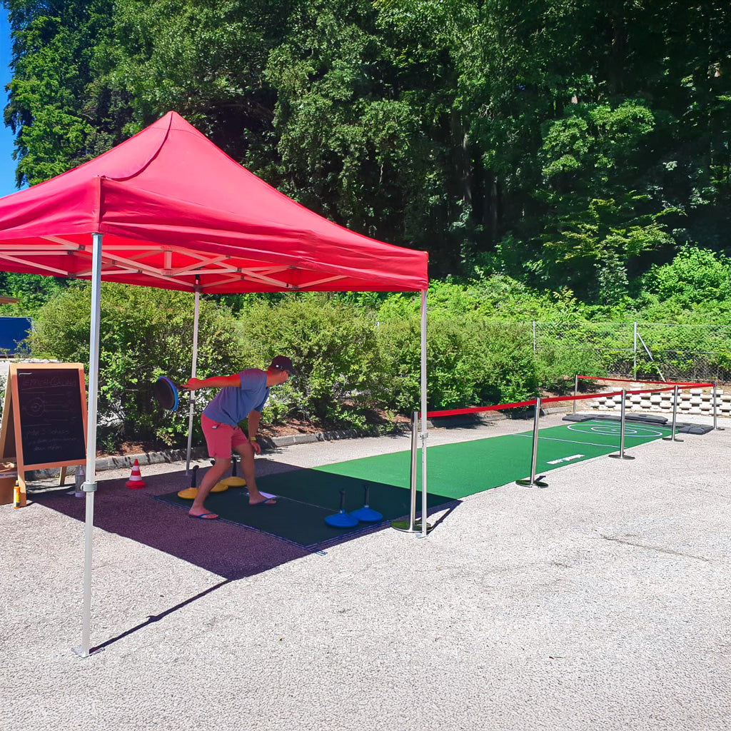 Eine Person die unter einem roten Zelt Teppichcurling spielt.