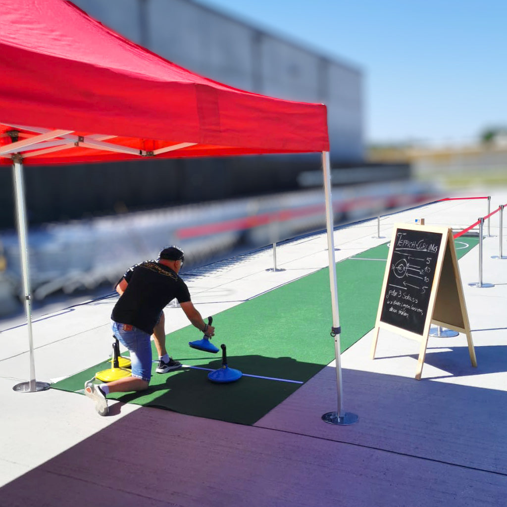 Eine Person die unter einem roten Zelt Teppichcurling spielt.