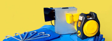 Hüpfburg Zubehör mit Gebläse, Erdankern und blauer PVC-Plane vor gelbem Hintergrund