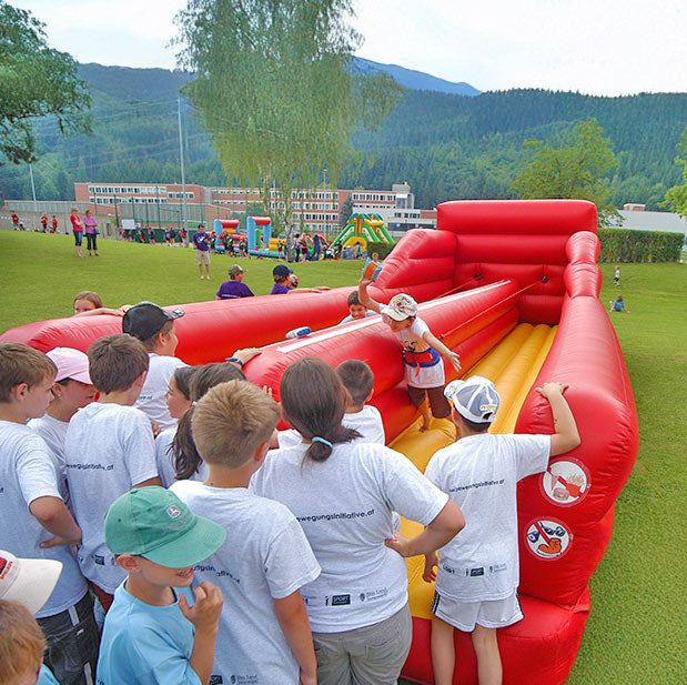 Kinder die an einem Seil in einem Bungee Run angebunden sind und einen Wettkampf veranstalten.