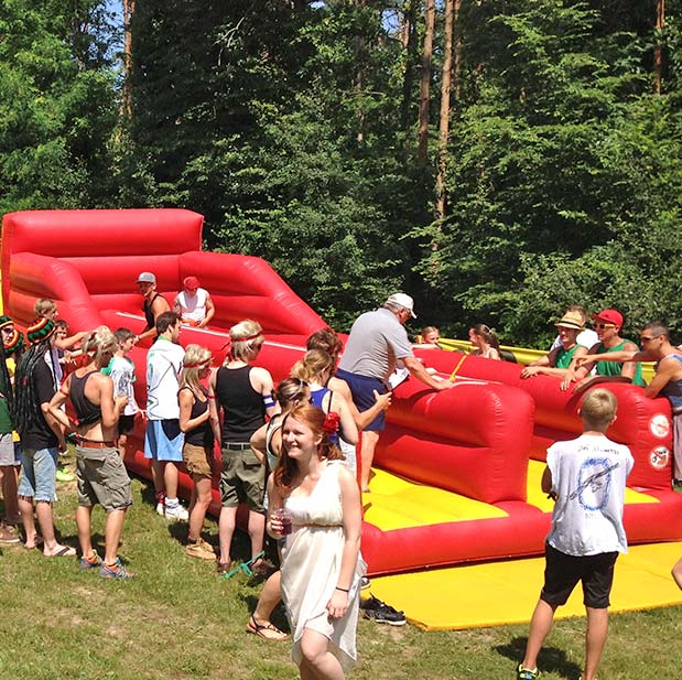 Viele Menschen bei einem Rot-Gelben Bungee Run neben Baeumen.