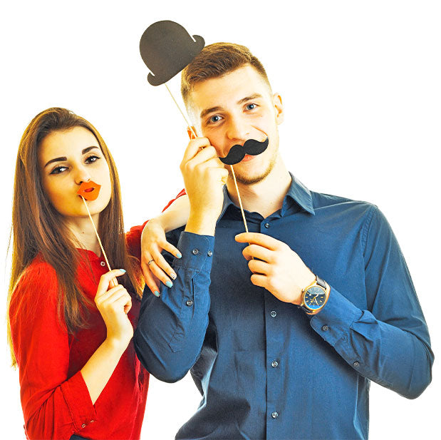 Eine Frau die sich rote Lippen zum Mund haelt und eine Mann der sich einen Hut auf den Kopf haelt und einen Schnurbart ober die Lippe