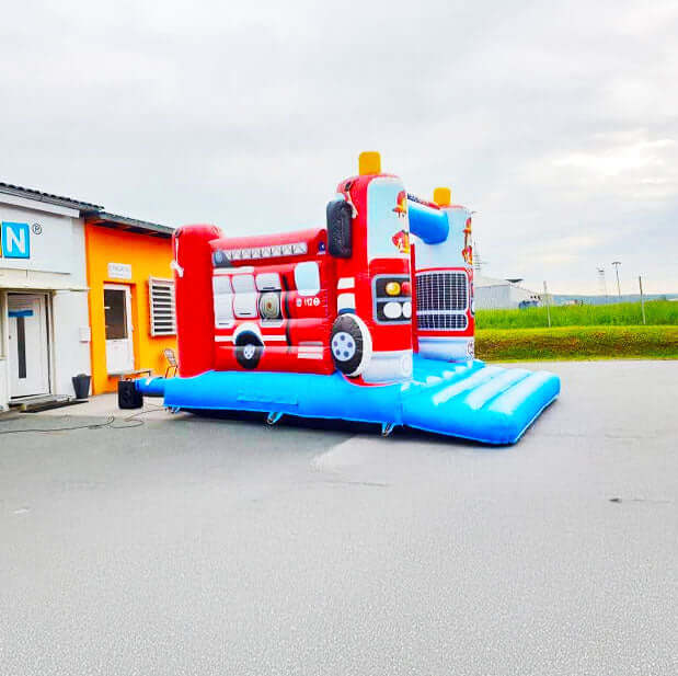Farbenfrohe Feuerwehr Huepfburg mit einem Geblaese hinten dran