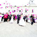 Froehliche Mensche die eine Hochzeit feiern und Herzluftballone steigen lassen 