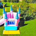 Bouncy castle in a castle look with elegant towers and a slide on a green meadow