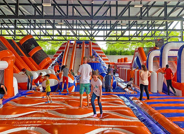 Viele Kinder springen auf einer Riesen Hüpfburg in einer großen Halle.Inflatable Park - Giant Bouncy Castle