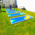 Froehliche Kinder die an einer blauen Mobilen Minigolfbahn spielen die auf einer Wiese aufgelegt ist.