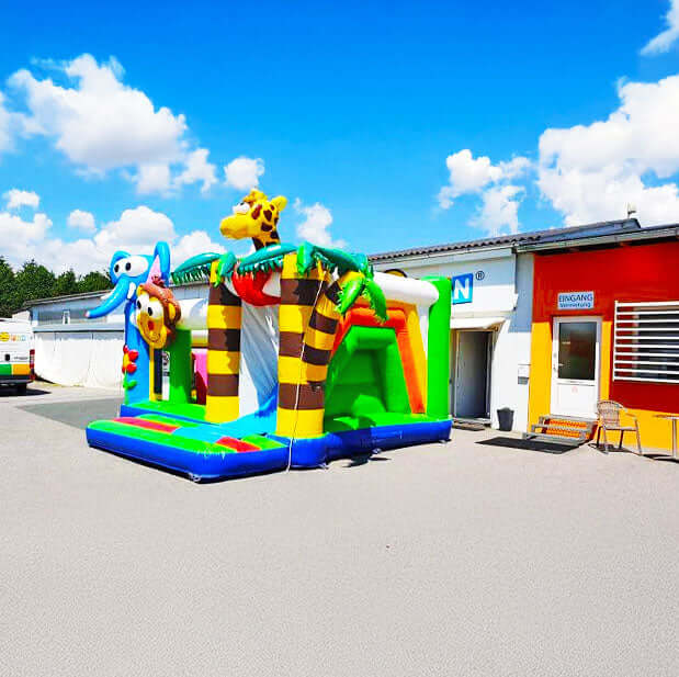 Farbenfrohe Dschungel Huepfburg mit Rutsche auf einem Betonplatz