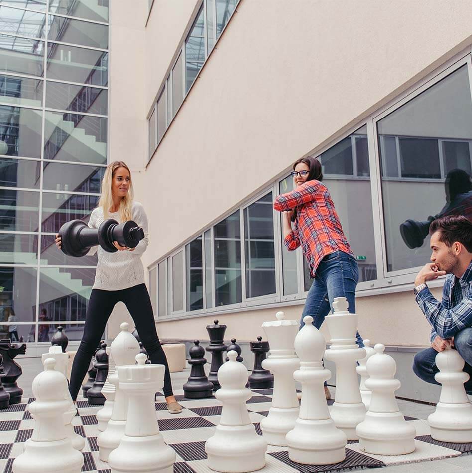 People play XXL chess with large chess pieces outdoors
