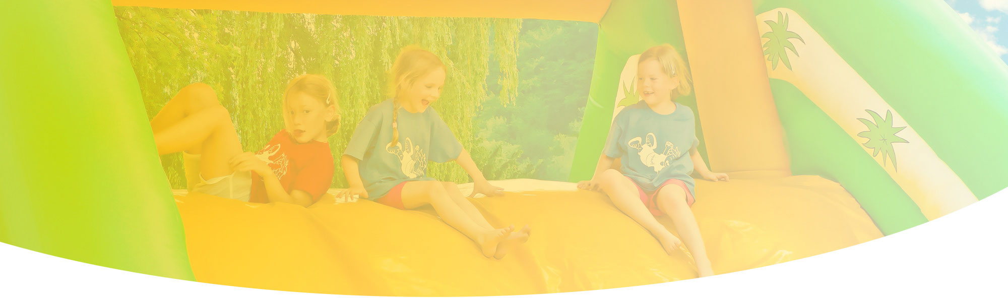 Fröhliche Kinder spielen lachend auf einer bunten happy Fun GmbH Hüpfburg im Freien