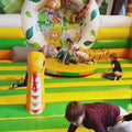 Runde aufblasbare Hüpfburg mit Dschungelmotiv und drehender Plattform; Kinder halten sich fest und erleben durch die Rotation zusätzlichen Spielspaß.