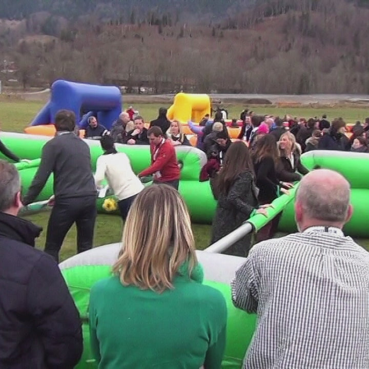 Erwachsene haben Spass in einem Riesenwuzzler der im freien steht.